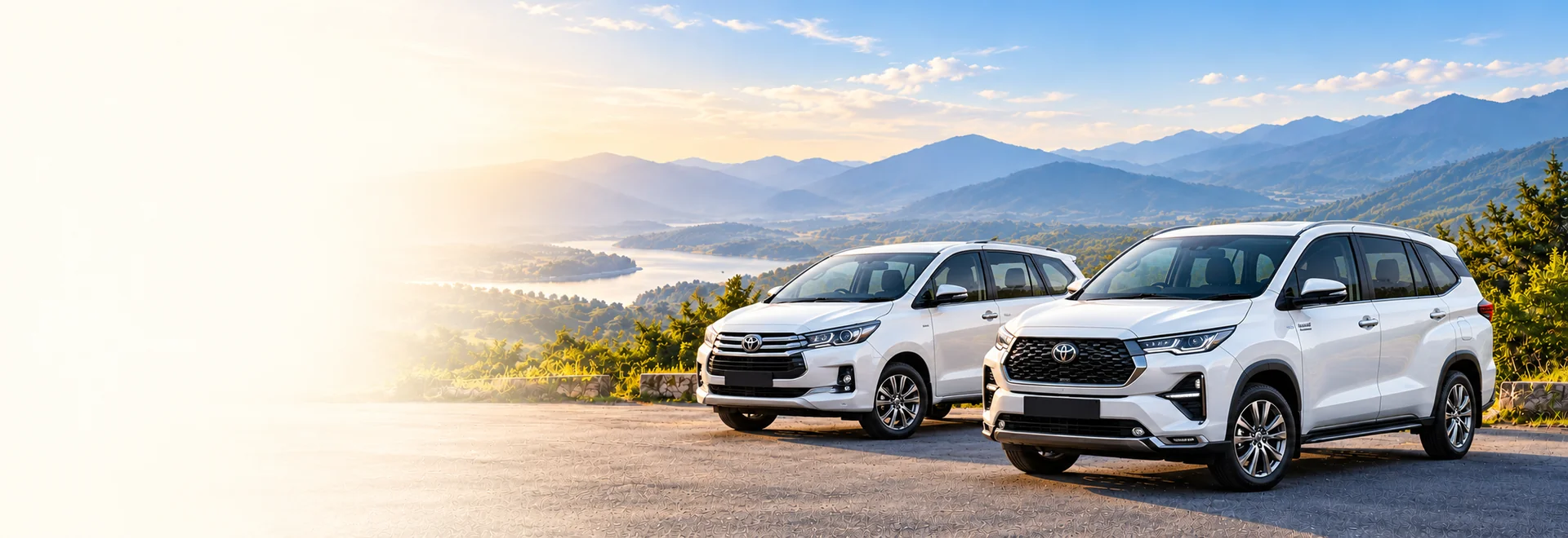 White Innova Crysta and Innova Hycross beside a scenic road